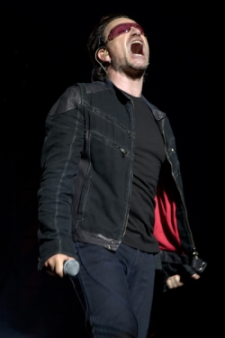 Zpěvák U2 Bono přichází po molu na malé pódium mezi diváky